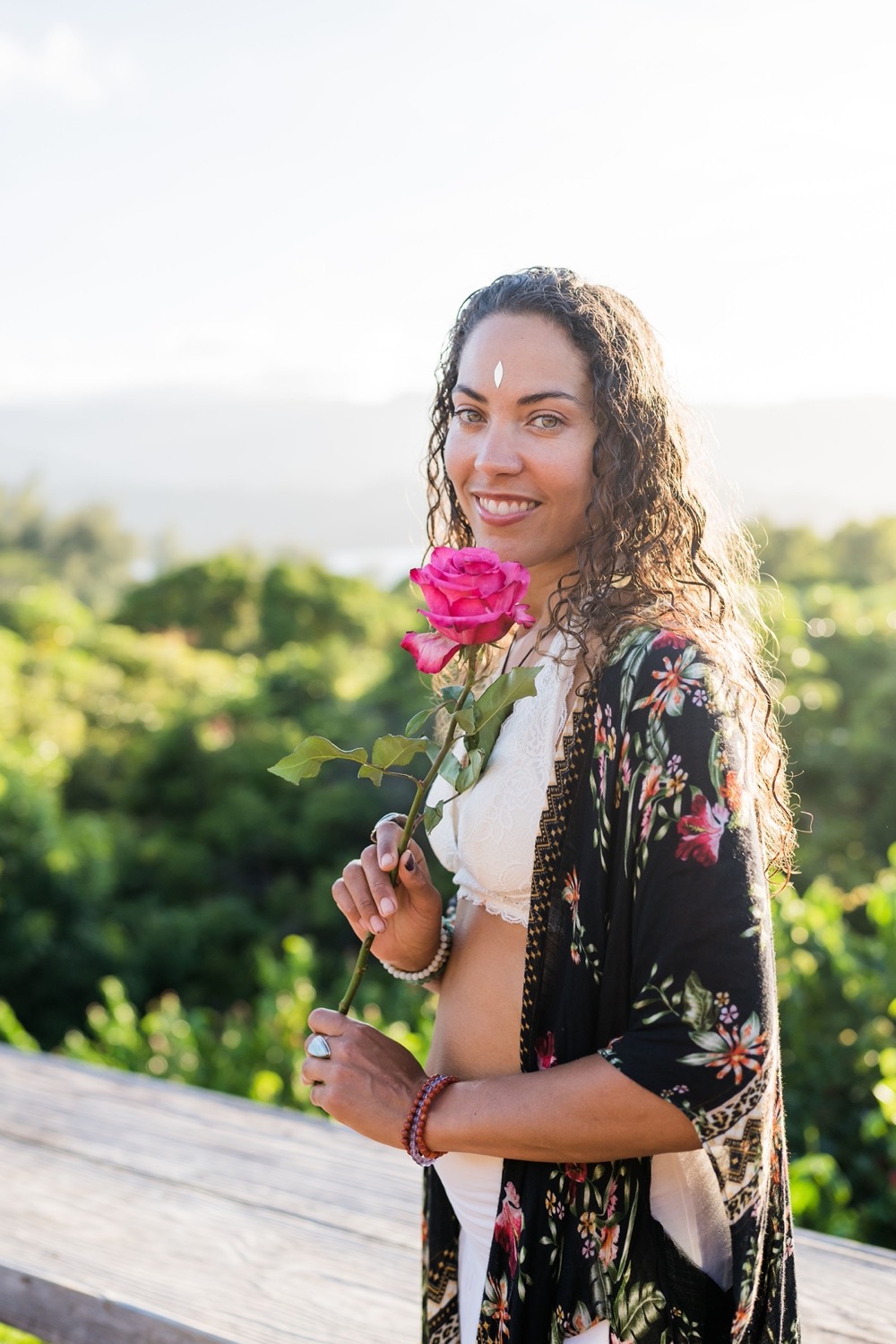 Donica Tomko holding a pink rose, wearing a floral kimono in golden light